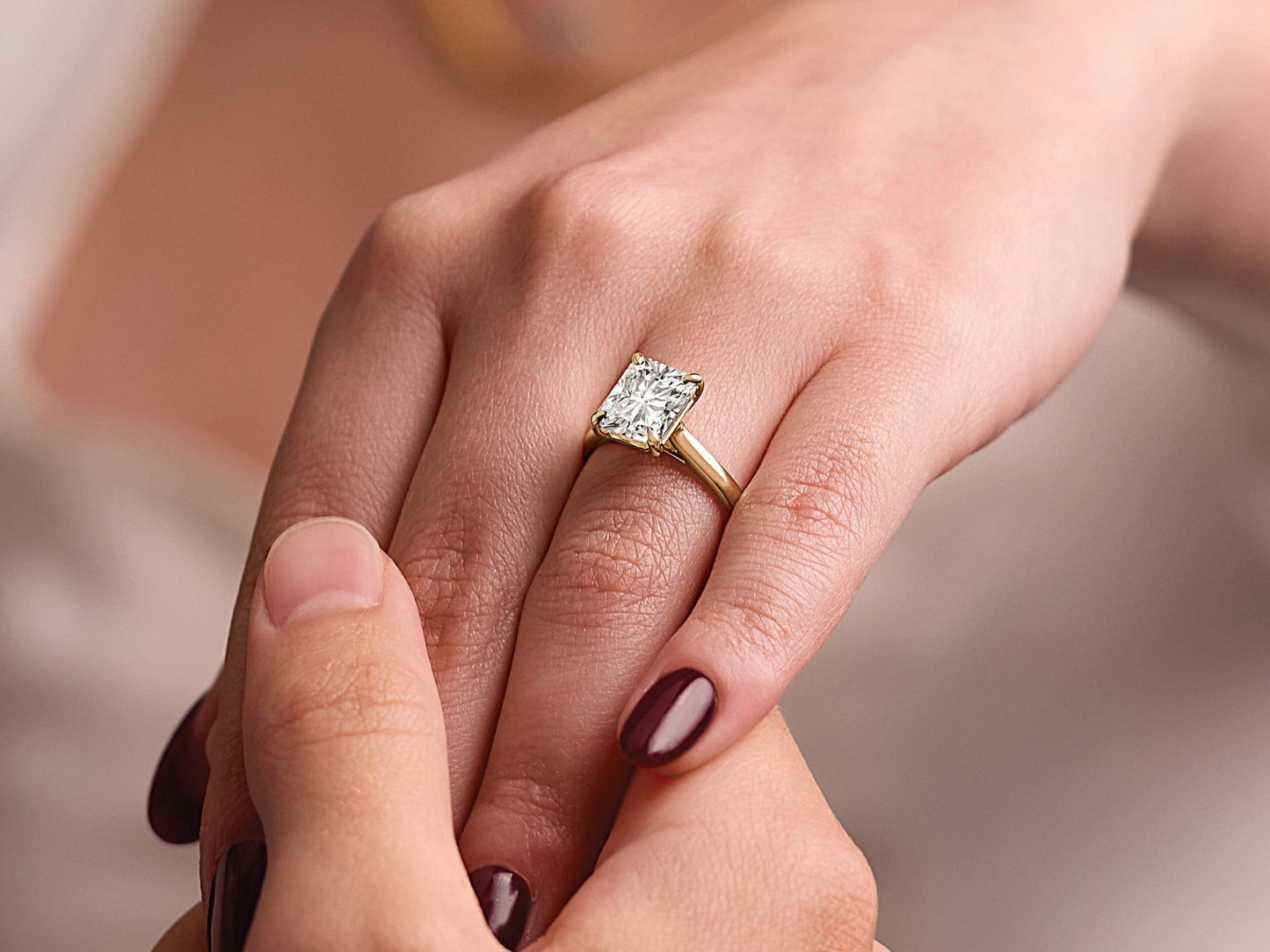 Close-up of a hand wearing a radiant-cut diamond engagement ring with a yellow gold band during a personal consultation session.