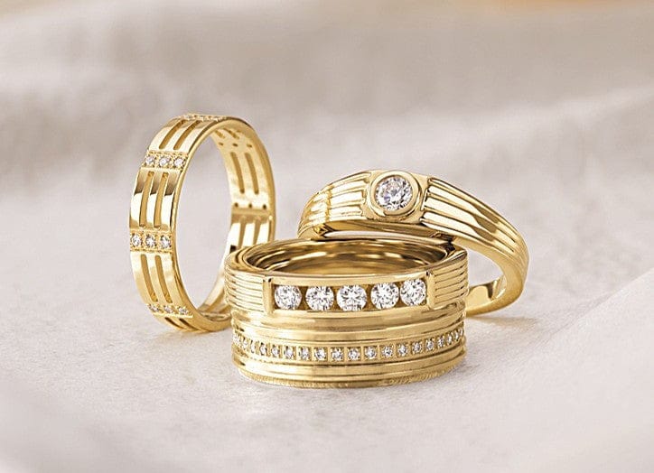 Three gold diamond eternity bands displayed on a soft, light-colored surface.