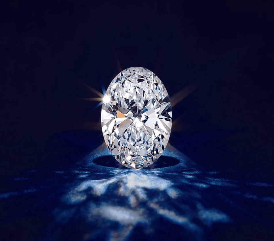 Oval-shaped lab grown diamond reflecting light on a dark surface, highlighting its brilliance for custom jewelry design consultation.