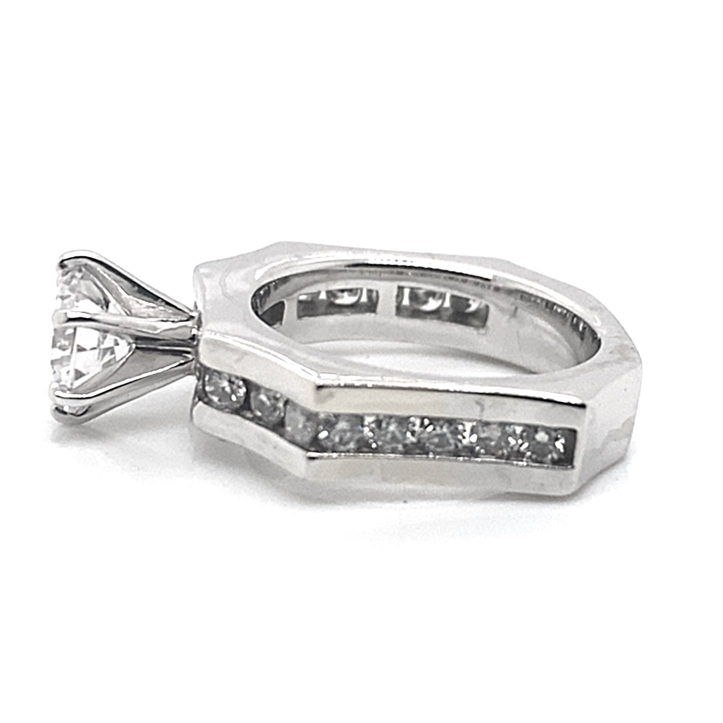 The 14K white gold ring showcases a prominent 6.5 mm round brilliant cut center stone, complemented by a half-carat of natural round brilliant diamond accents, elegantly inlaid into the concaved octagon band design.