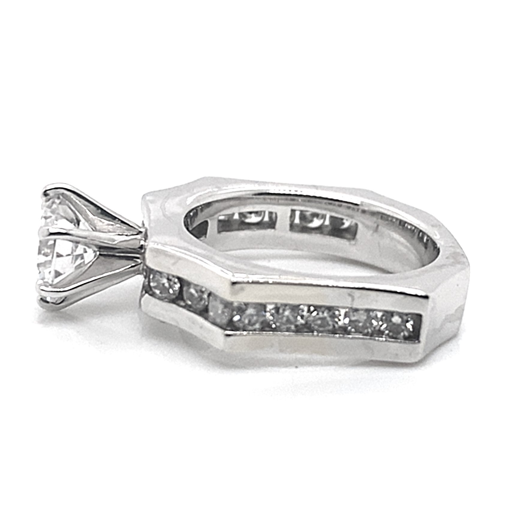 The 14K white gold ring showcases a prominent 6.5 mm round brilliant cut center stone, complemented by a half-carat of natural round brilliant diamond accents, elegantly inlaid into the concaved octagon band design.