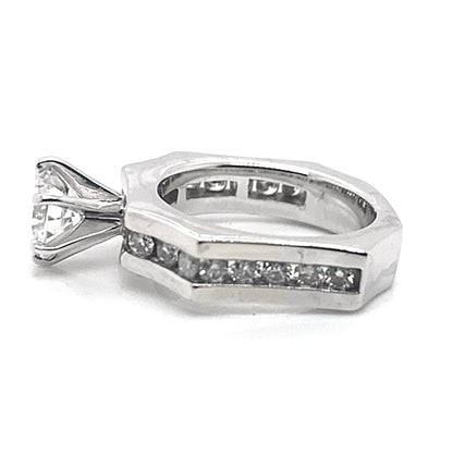 The 14K white gold ring showcases a prominent 6.5 mm round brilliant cut center stone, complemented by a half-carat of natural round brilliant diamond accents, elegantly inlaid into the concaved octagon band design.