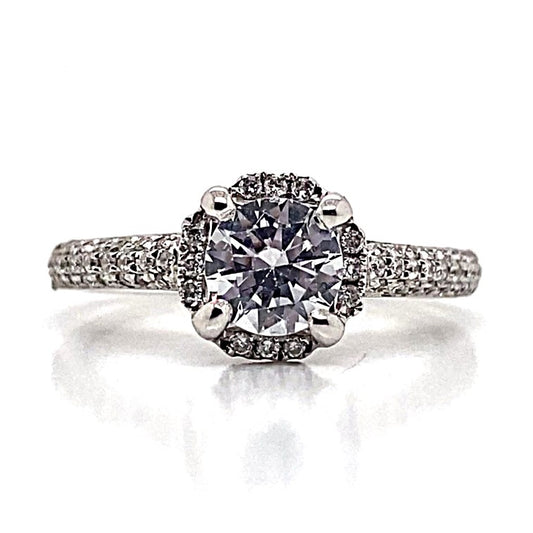 A dazzling 18K white gold ring with a 6.5 mm CZ center, surrounded by a halo of natural round brilliant diamond accents totaling .28 carats, ideal for special occasions and beautifully showcased on a reflective surface.