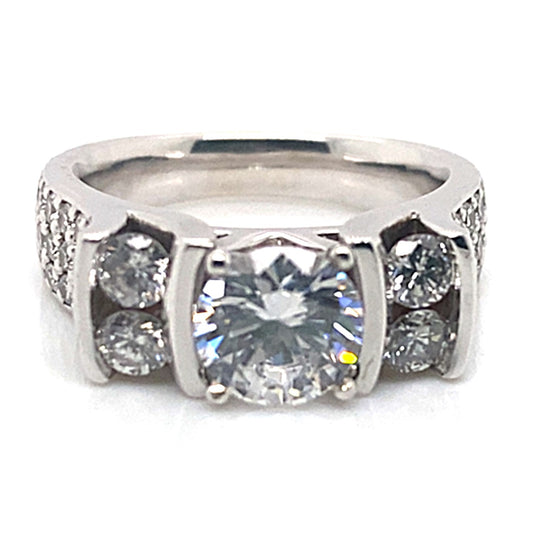 A breathtaking 14K white gold engagement ring showcases a prominent central CZ stone, highlighted by channel side pave accents with smaller stones along the band.