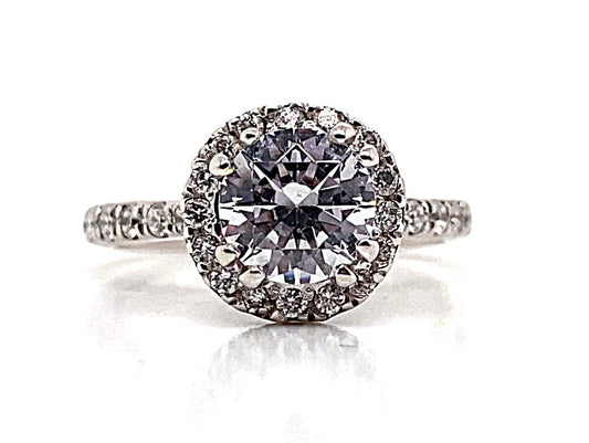 A 14K white gold engagement ring in a round halo style, featuring a prominent 6.5 mm RBC CZ center stone, complemented by .50 ct TW natural round brilliant diamond accents.