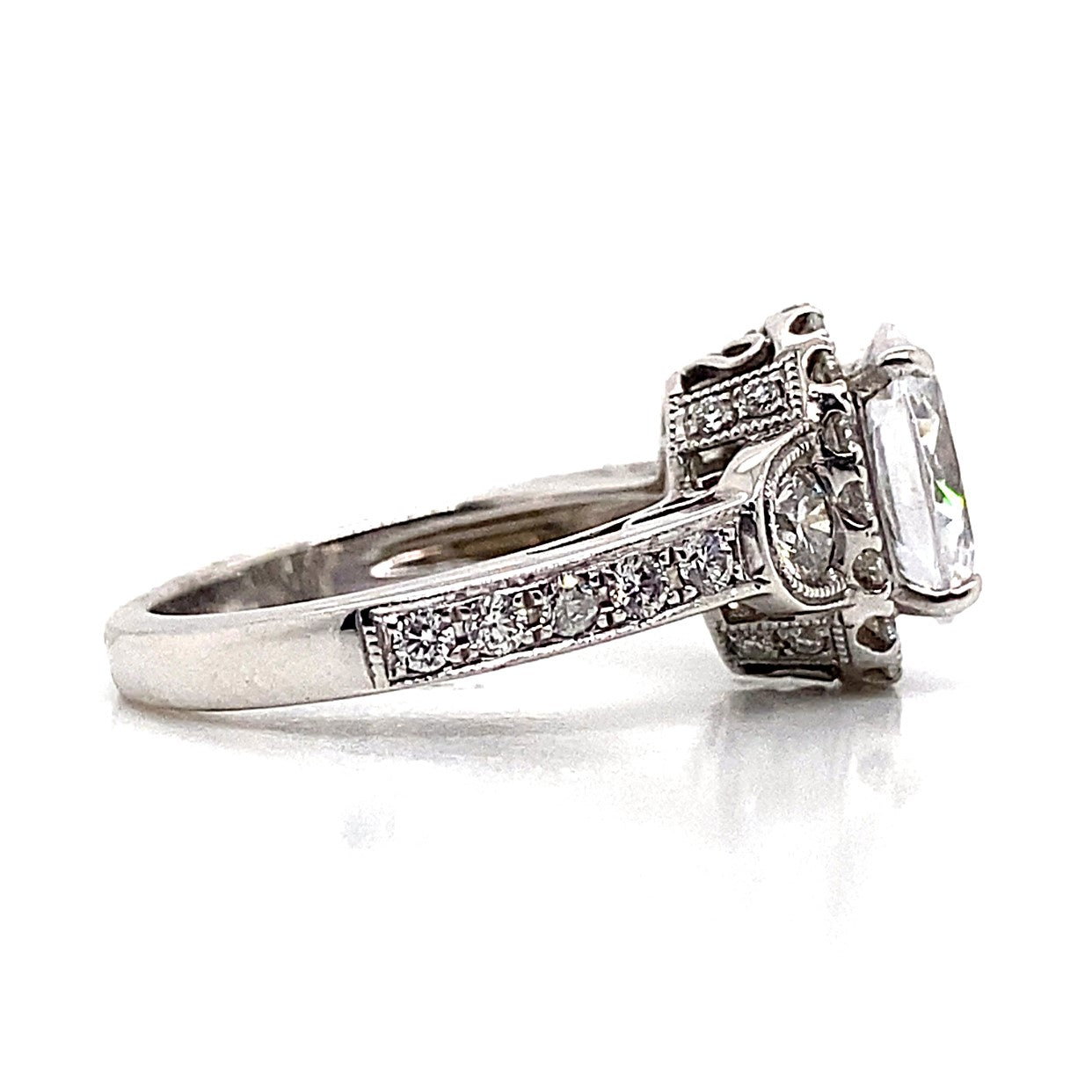 Side view of an exquisite 14K white gold engagement ring, showcasing a captivating oval CZ center stone with a total weight of .75 carats, surrounded by a halo design and enhanced by brilliant natural round diamond accents on the band.