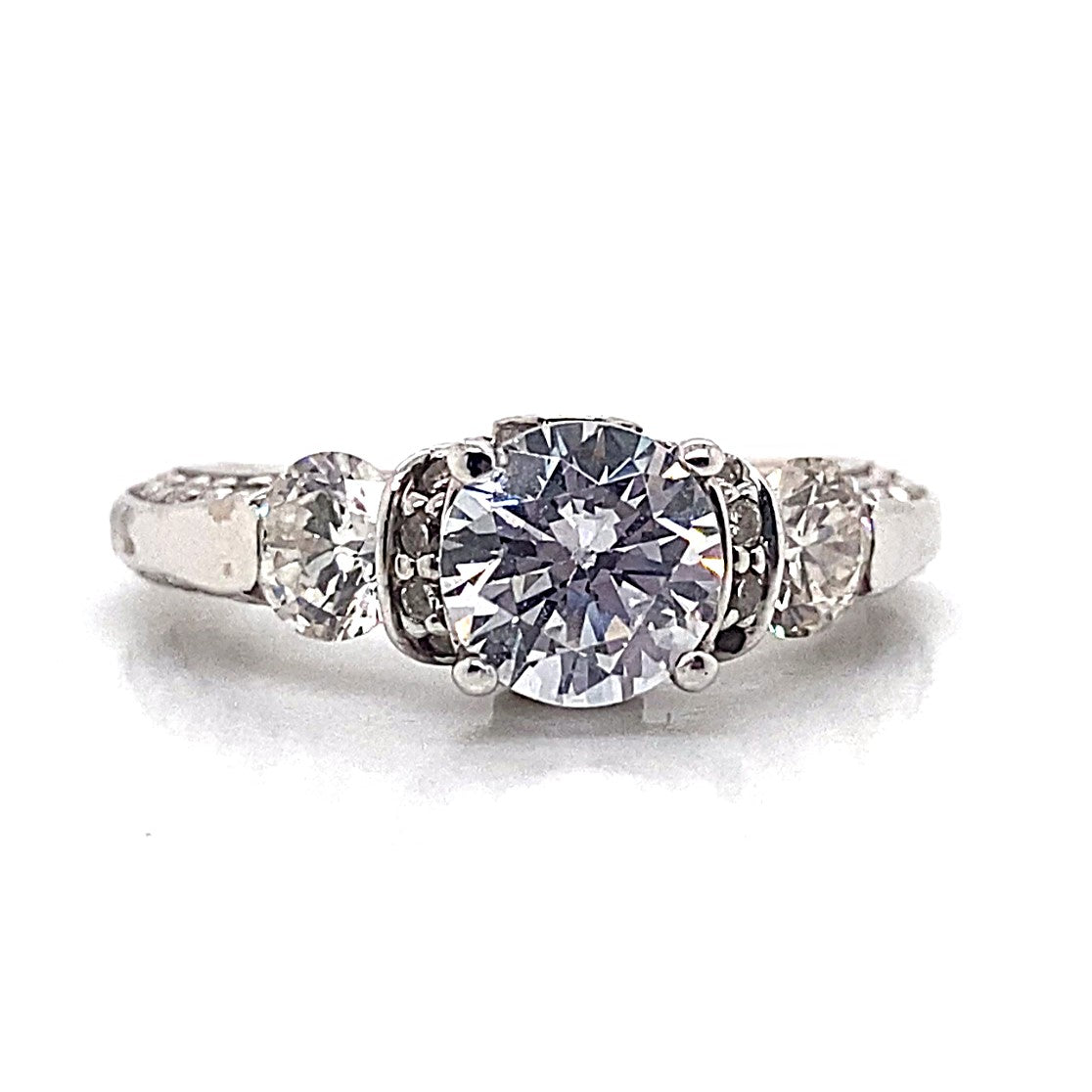 A captivating 14K white gold engagement ring showcases a prominent 7 mm round brilliant cubic zirconia centerpiece, accompanied by natural round brilliant diamond accents in a three-stone pave design.