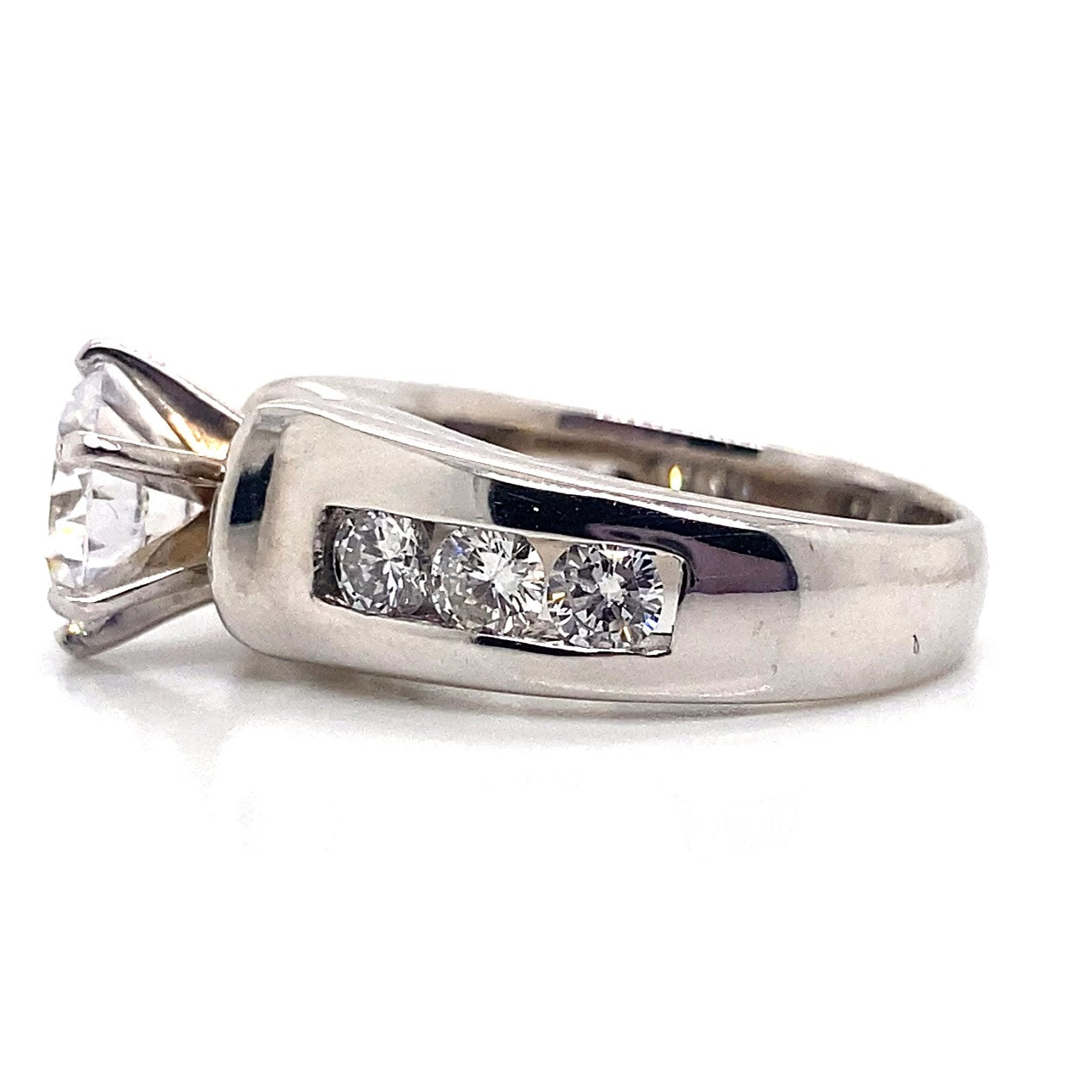 A stunning 14K white gold ring showcasing an 8.5mm RBC CZ center stone, enhanced with a total of 1.25 carats of natural round brilliant diamond accents channel set along the band.