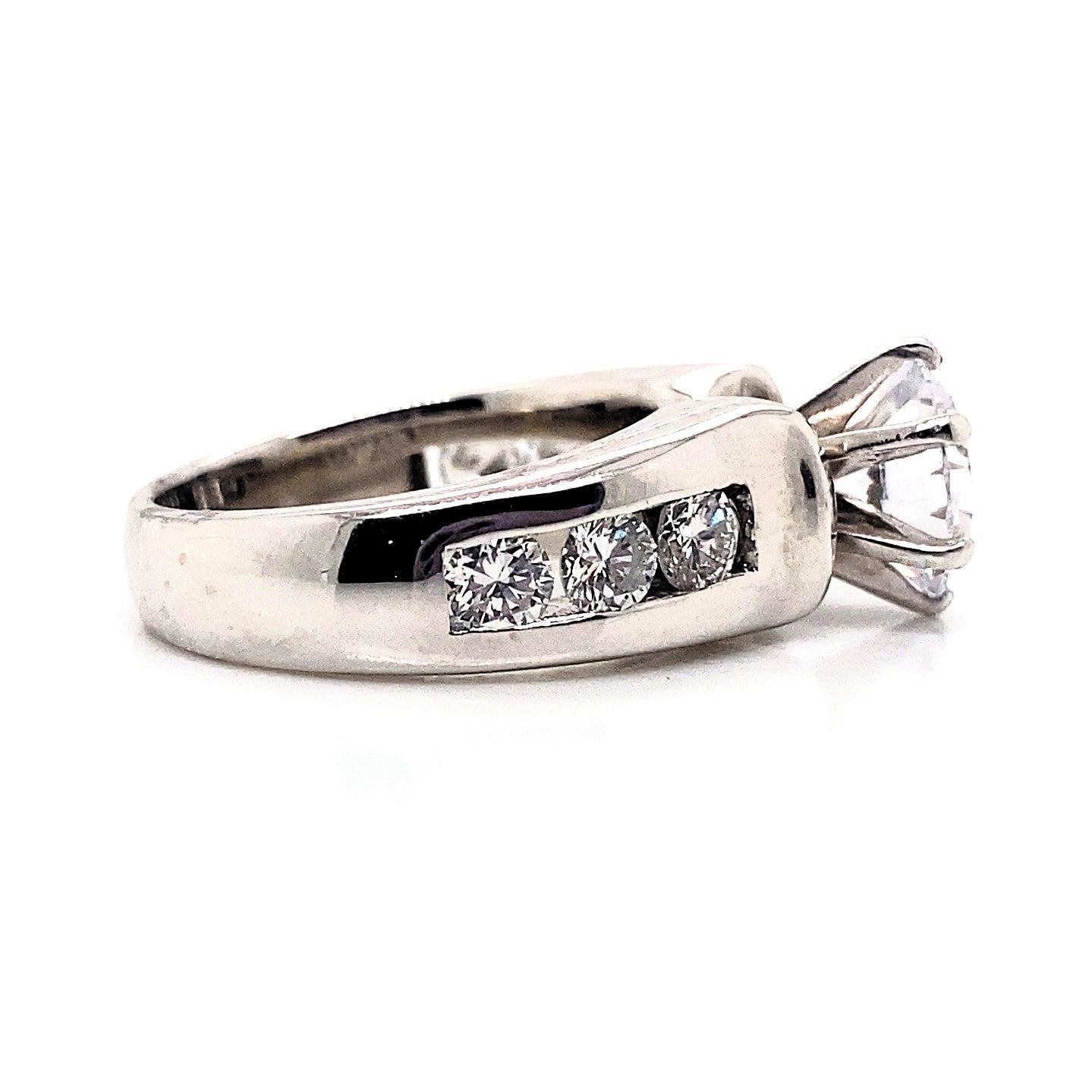 This exquisite ring showcases a CZ center gemstone measuring 8.5mm in 14K white gold, complemented by natural round brilliant diamond accents with a total weight of 1.25 carats, all elegantly channel set.