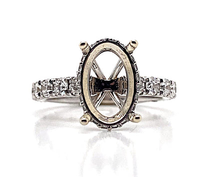 A masterfully crafted 14K white gold ring setting, designed for a 10x6 mm oval gem, features a hidden halo with 1.50 carats total weight of natural round brilliant diamond accents on the band.