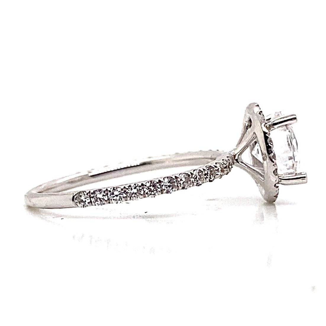 Side view of an 18K white gold engagement ring with a halo style and diamond-accented slender band.