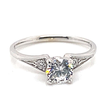 14K white gold engagement ring with a central 6mm round brilliant cut cubic zirconia, complemented by .10 carat total weight of natural round diamonds, elegantly arranged in a 3-stone filigree design.