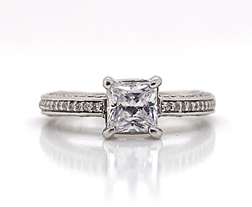 An exquisite 14K white gold engagement ring with a 5.5mm princess cut CZ at its center, complemented by .65 ct total weight of natural round brilliant diamond accents along the square shank band.