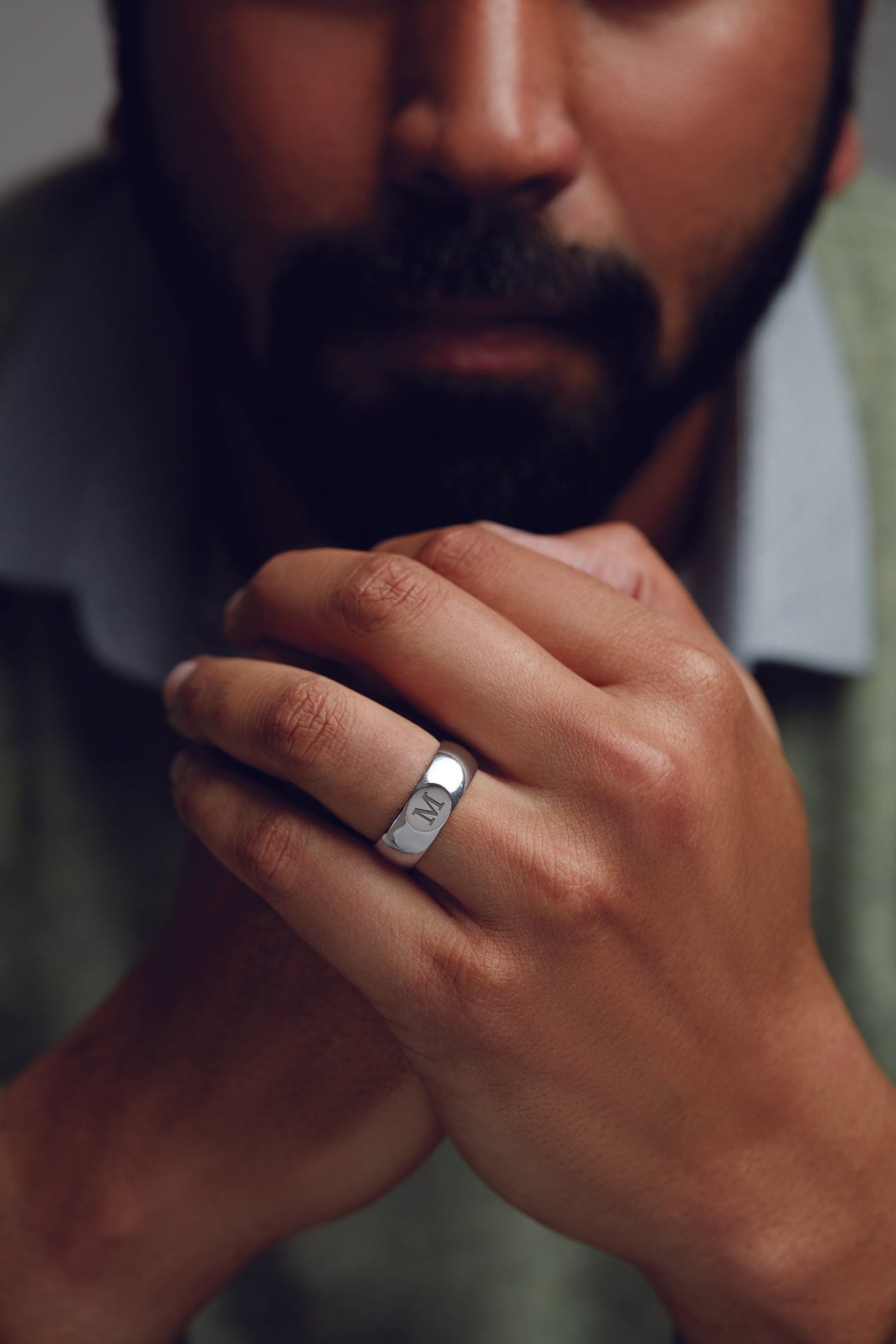 Close-up of a man's hand wearing a silver ring with a blurred background
