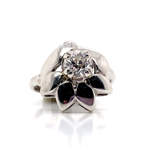 A 14K White Gold ring with a round European cut natural diamond, SI2/H-I clarity, totaling .65 carats at its center, elegantly arranged in a flower design on a reflective surface.