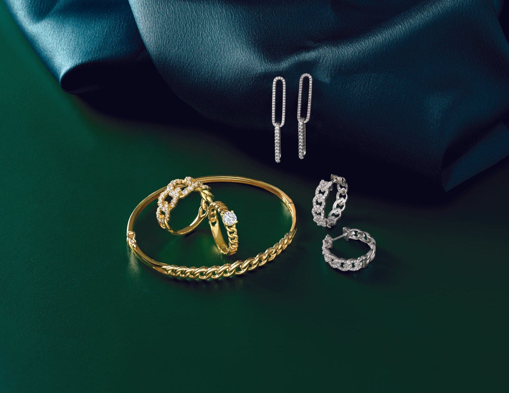 ladies white gold and yellow gold jewelry laying on a green surface