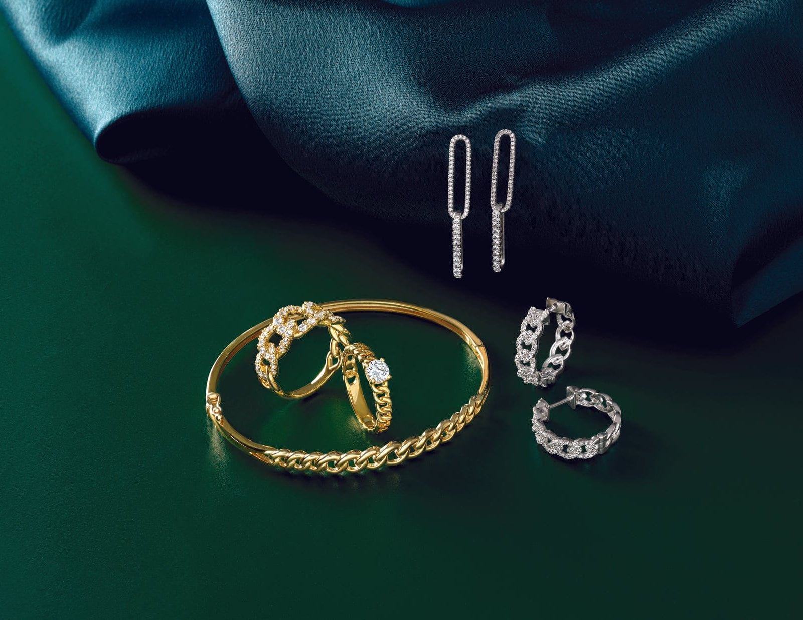 white gold and yellow gold fashion jewelry set on a dark green fabric background