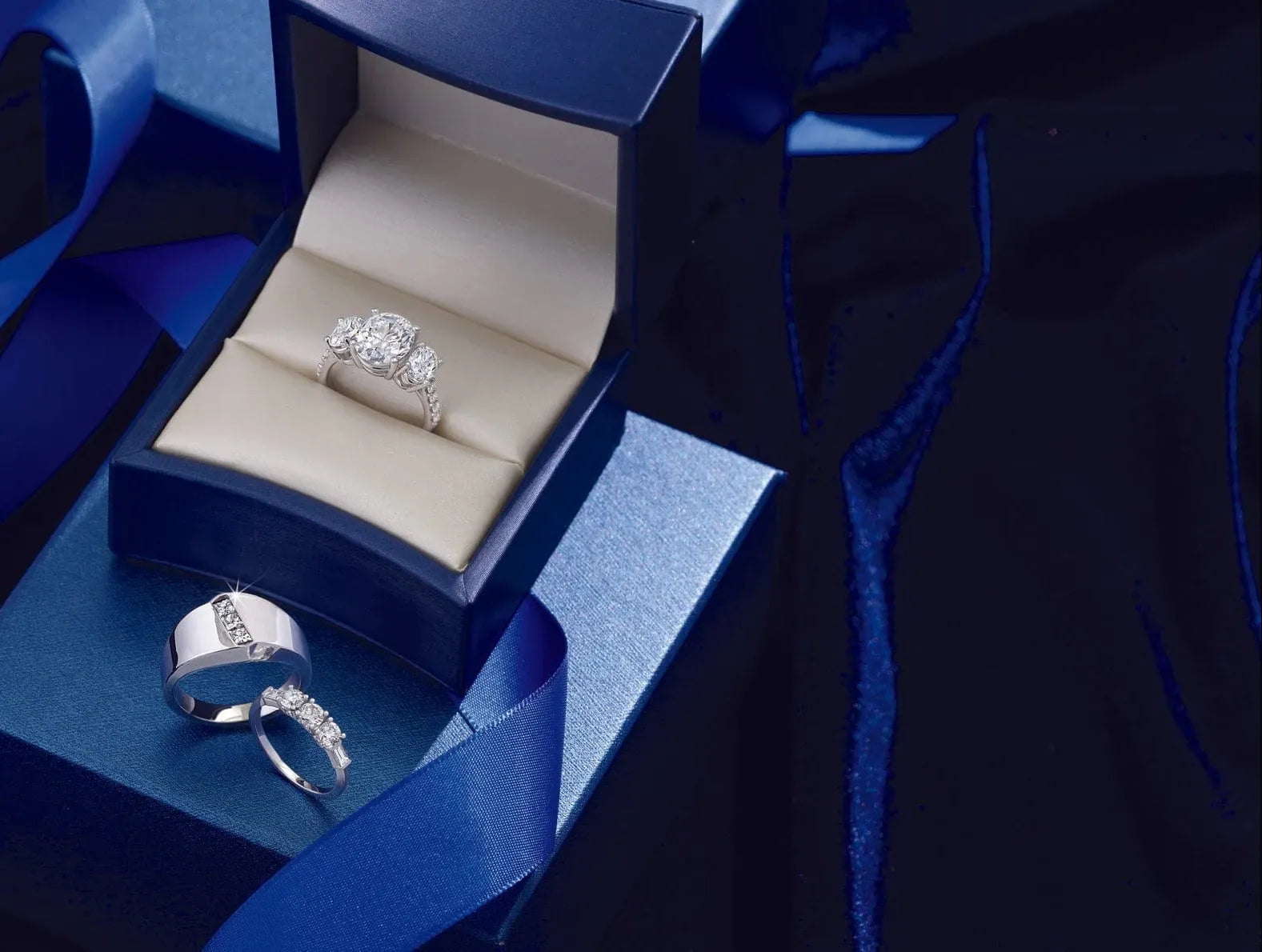 white gold engagement ring in an open blue jewelry box with a dark background