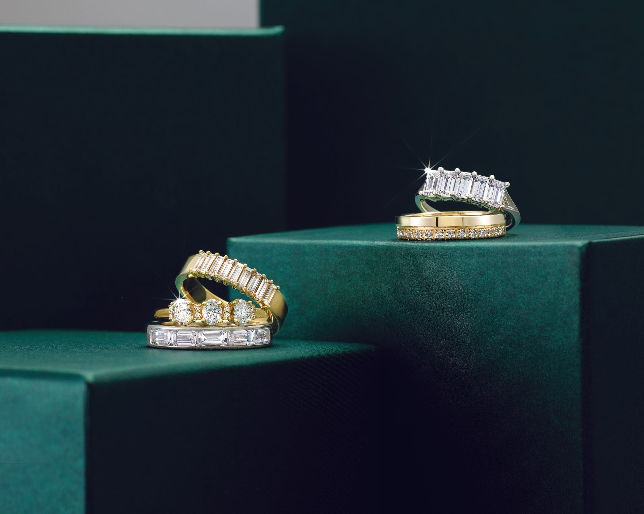 gold and diamond eternity bands on green boxes against a dark background