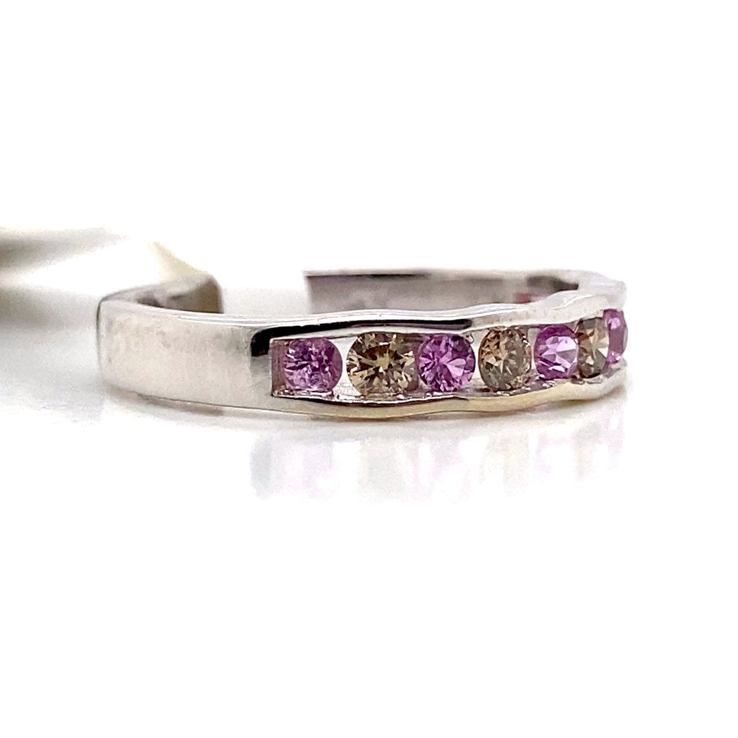 This 14K white gold ring showcases a wavy band embellished with alternating natural pink sapphires totaling .30 carats and .25 carats of natural chocolate diamonds in a captivating row.