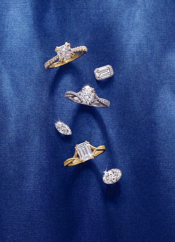 Collection of trendy diamond engagement rings on a blue fabric background