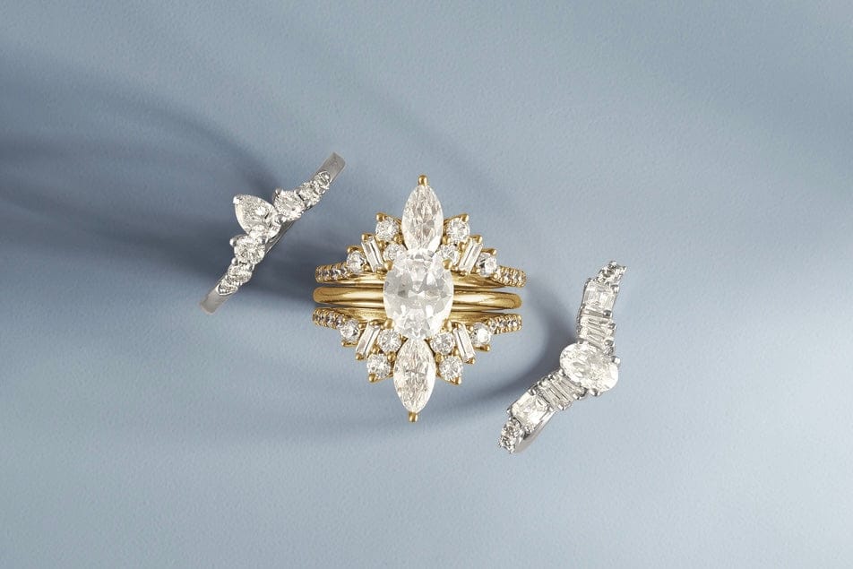 Three diamond engagement rings with gold bands arranged on a light blue background.