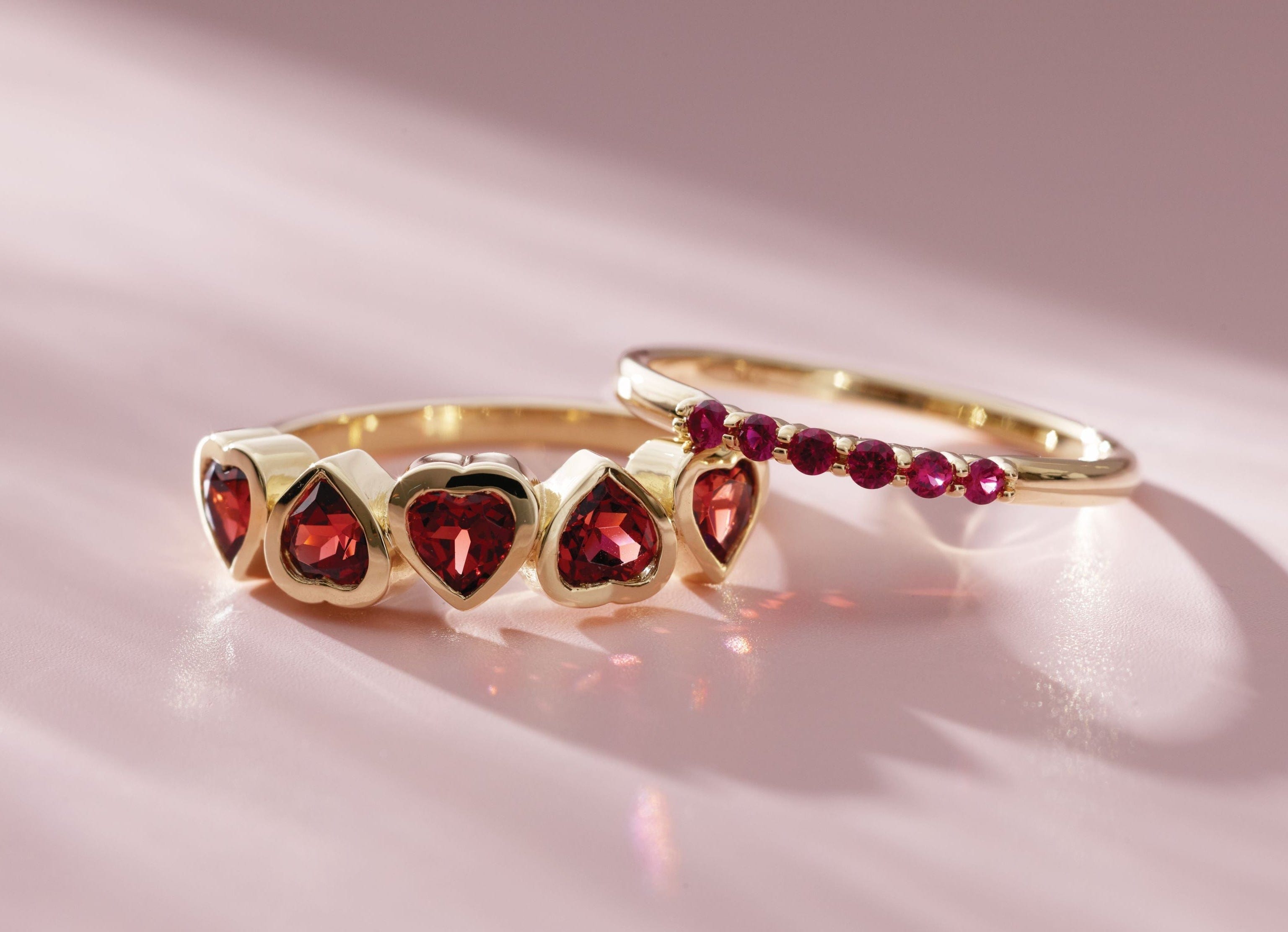 Two ruby rings with red gemstones on a pink background