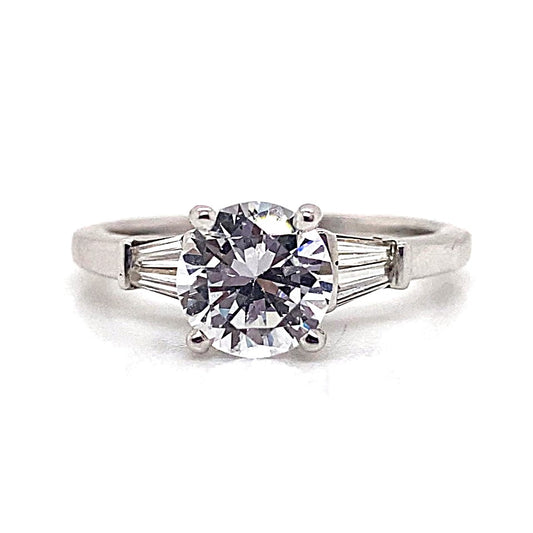 A captivating 14K white gold ring features a round cubic zirconia centerpiece, flanked by two tapered baguette natural diamond accents on the sides, totaling .60 carats.