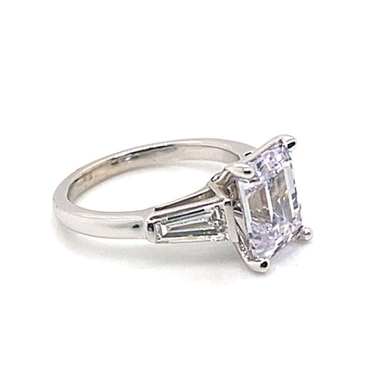 A 14K white gold engagement ring boasts a prominent 9x7mm emerald-cut center stone, beautifully complemented by .70 CT TW natural baguette diamond accents, all in G/VS quality.