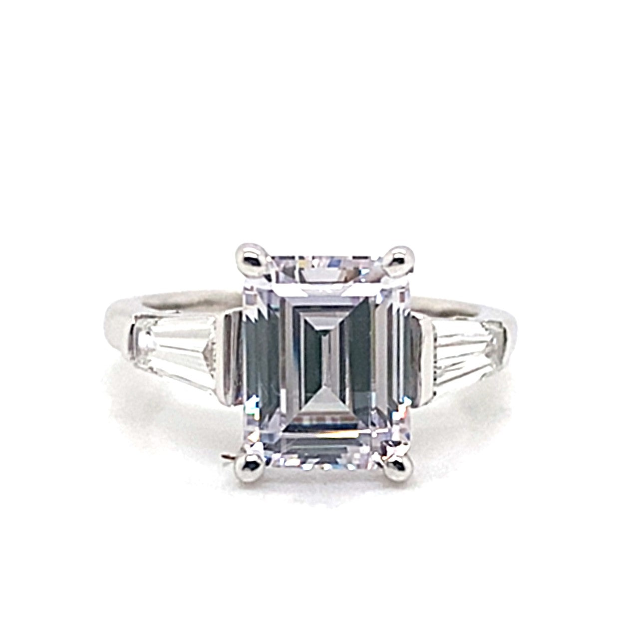 This stunning 14K white gold engagement ring showcases a 9x7mm emerald cut CZ center stone complemented by .70 carat total weight of natural baguette diamond accents, all set on a luminous band.