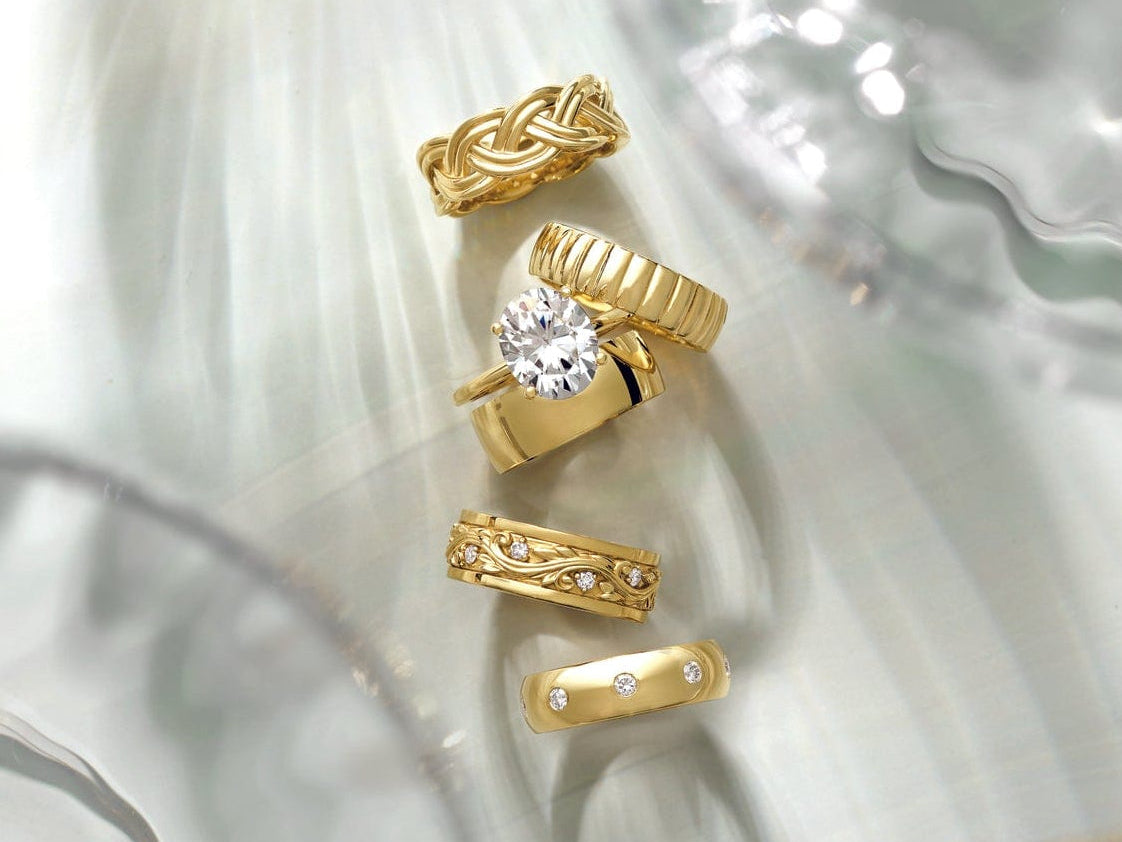 Set of gold lab grown diamond engagement rings with various designs on a textured white surface