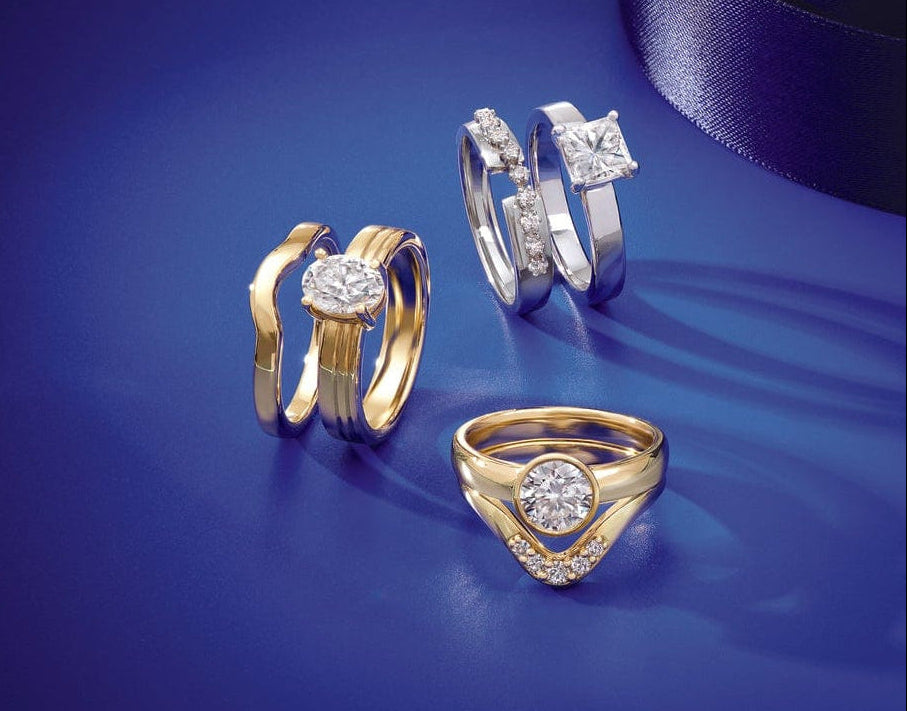 Three gold and silver enagement ring sets with lab grown diamonds on a blue background