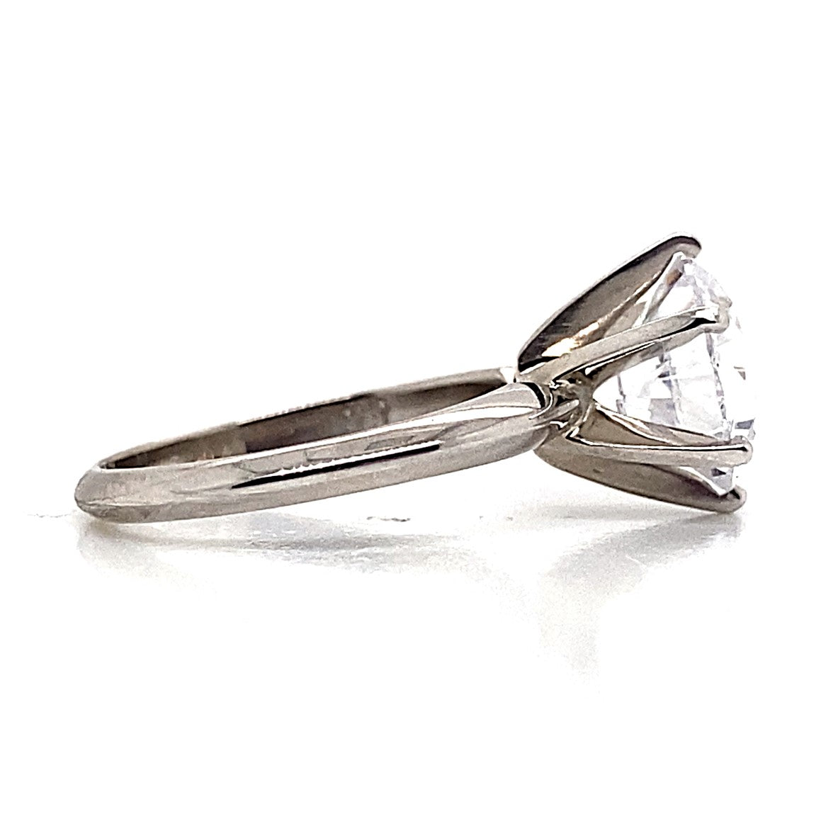 14K white gold solitaire ring in the Tiffany style, featuring a captivating 9mm round brilliant cut CZ in a prong setting, elegantly displayed on a reflective surface.