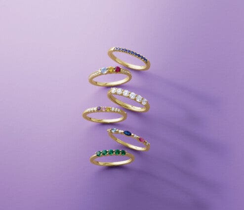 Set of gold rings with colored gemstones on a purple background