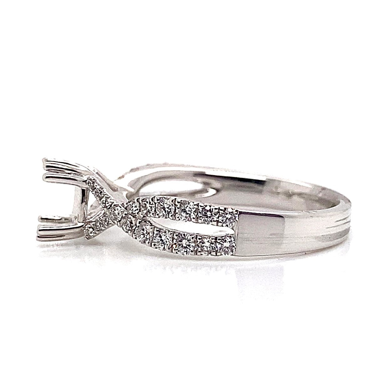 Infinity style ring crafted from 18K white gold, featuring natural round brilliant diamond accents with a twisted band and silver prong setting.