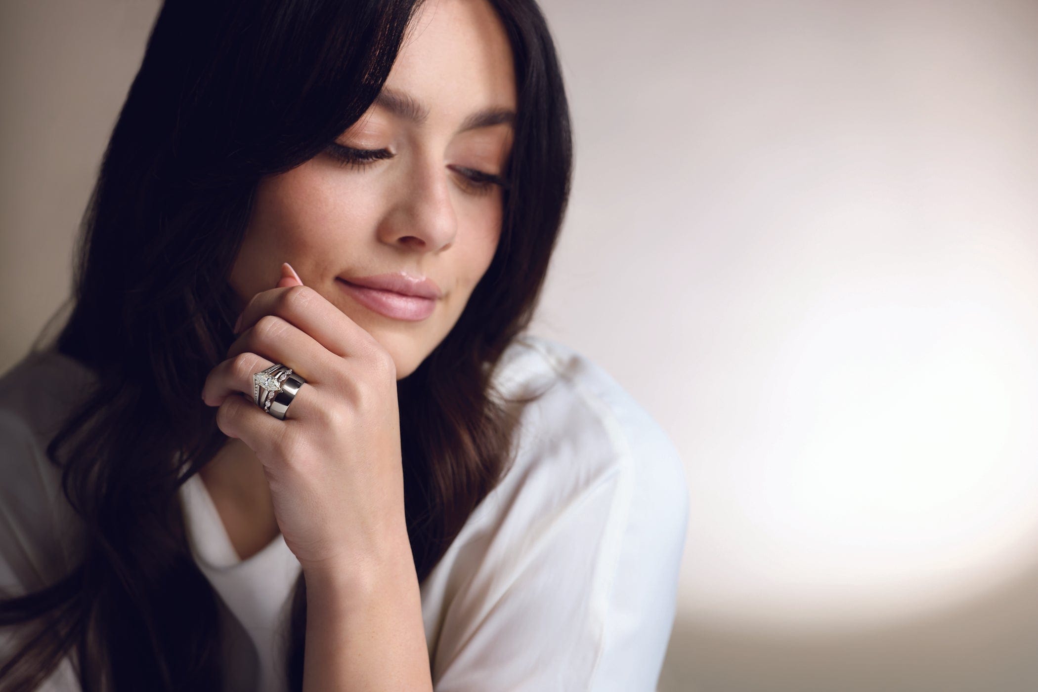 Woman with dark hair and a ring on her finger, wearing a white top at Christopher Fine DIamonds jewelry store.