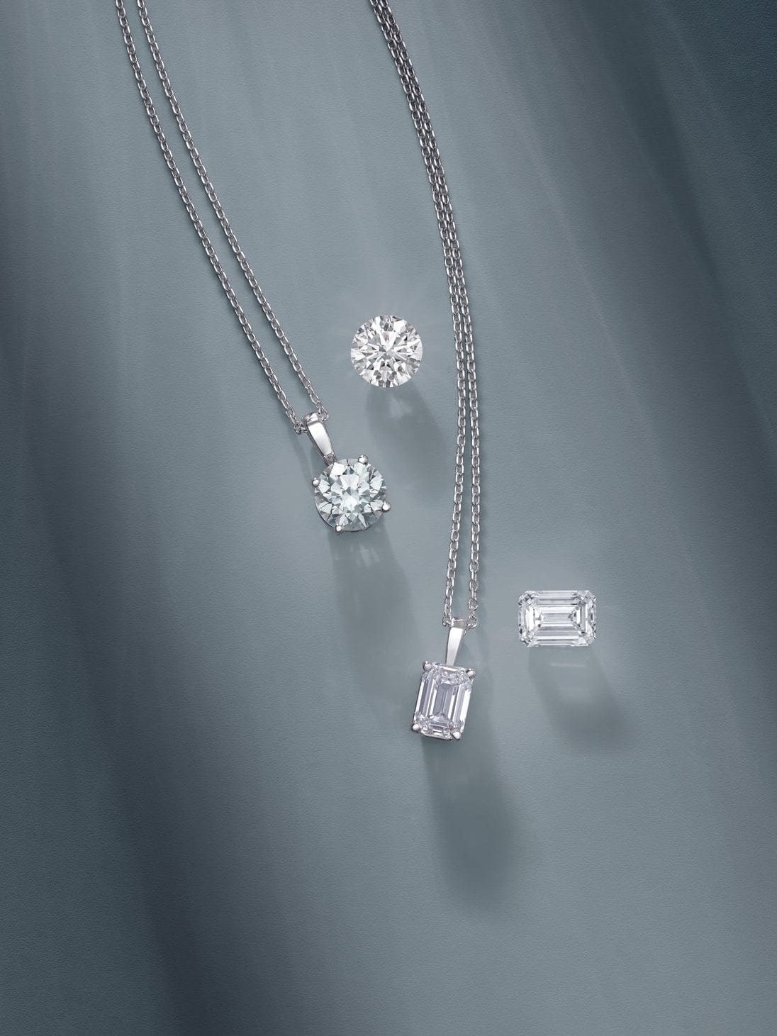 Three diamond pendants on a chain against a teal fabric background