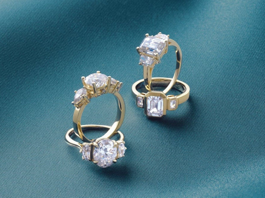 modern bezel engagement rings with diamonds on a teal fabric background