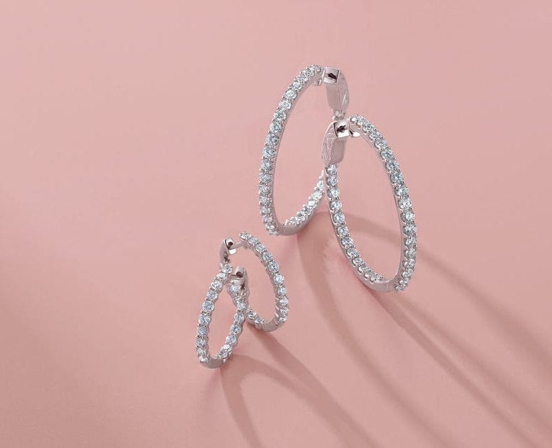 Pair of diamond hoop earrings on a pink background