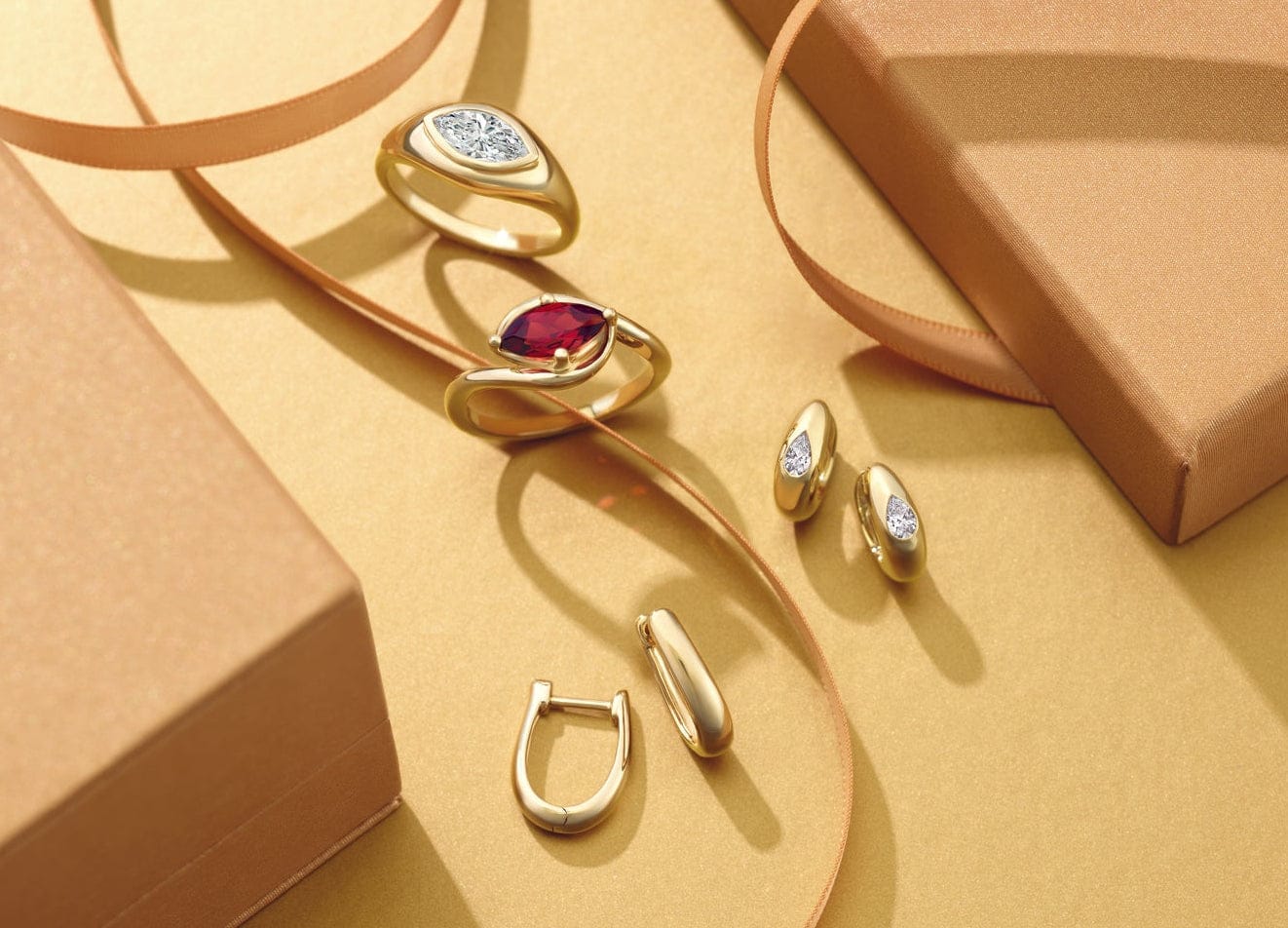 Gold jewelry set with gemstone rings and gold fashion earrings on a yellow surface