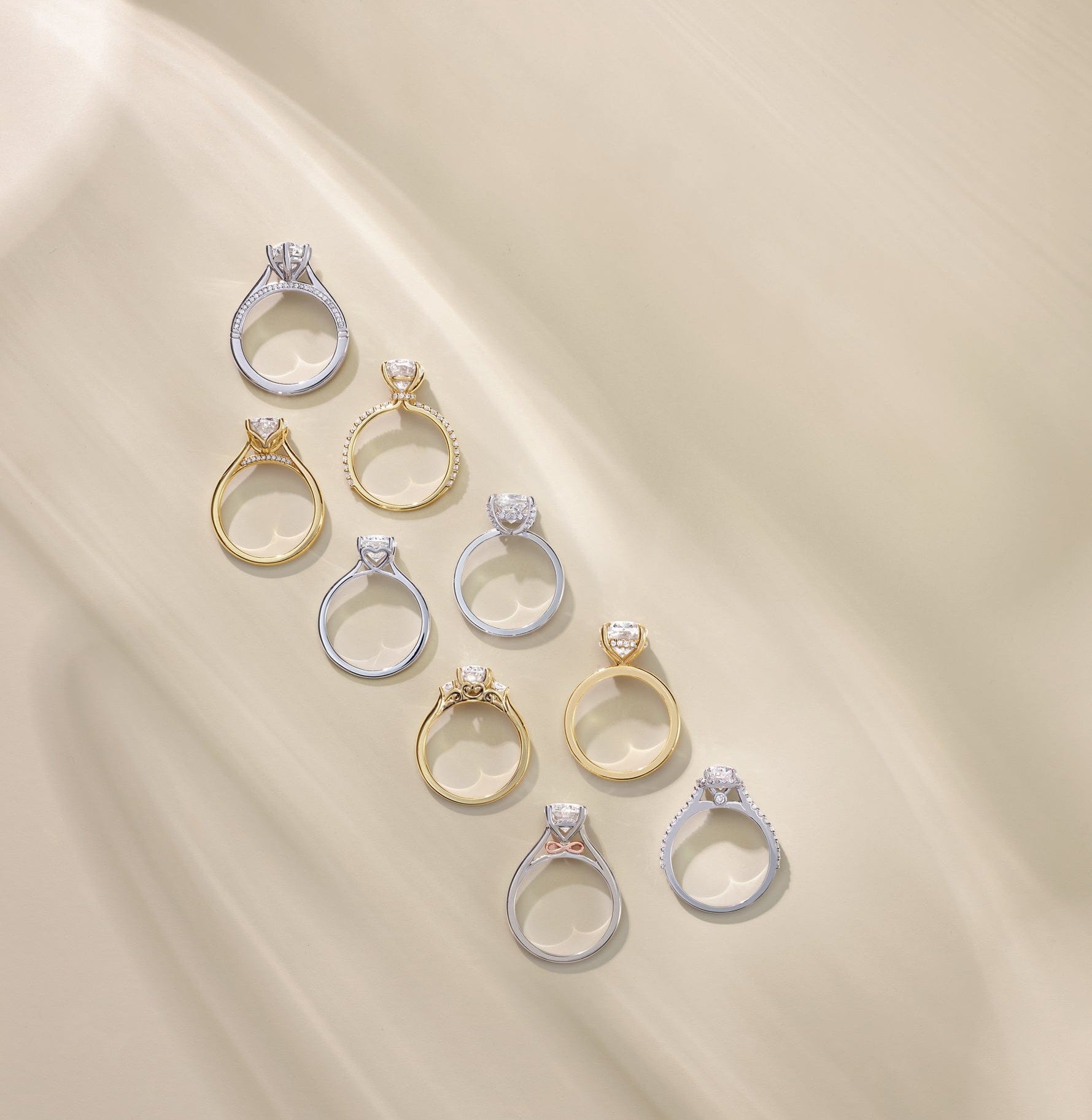 Collection of various lab diamond diamond engagement rings on a beige fabric background