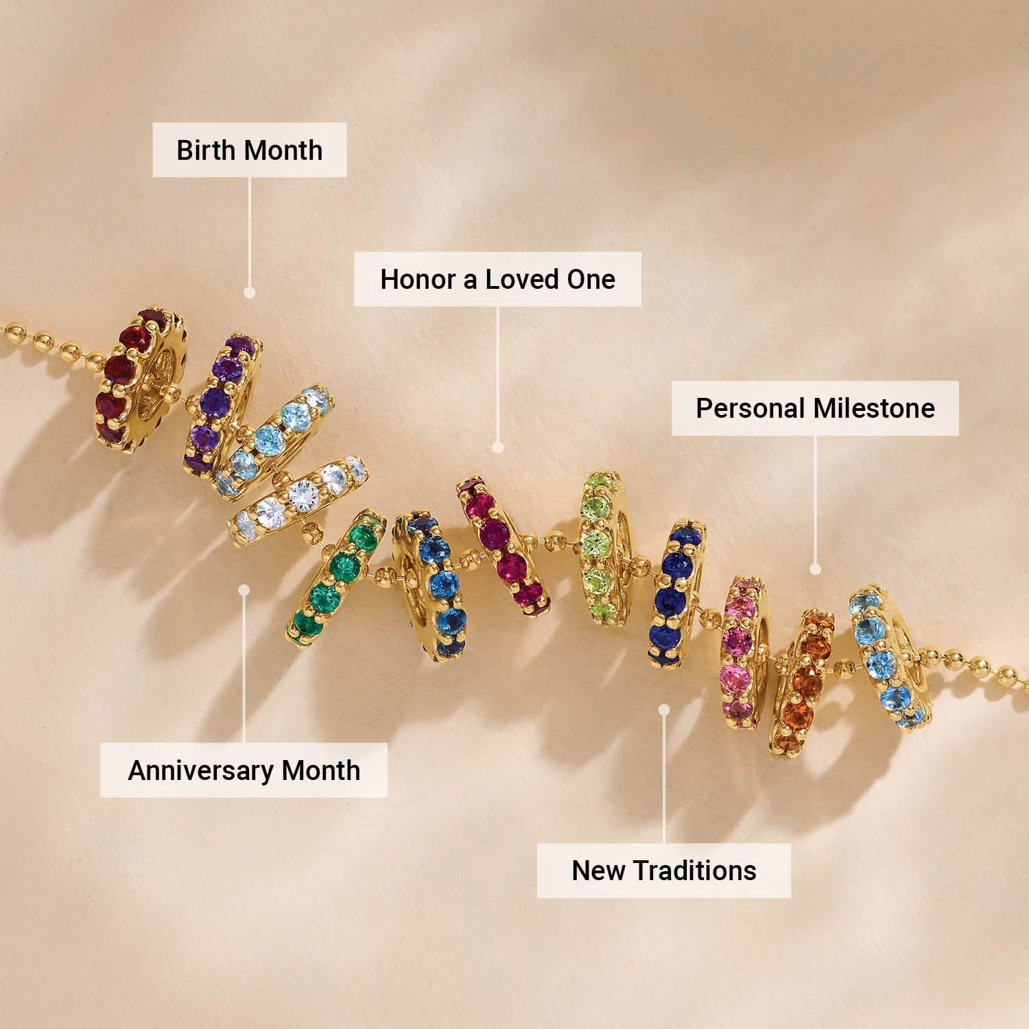 Gold rings with colorful gemstones on a chain, each labeled for milestones like birth month and anniversary.