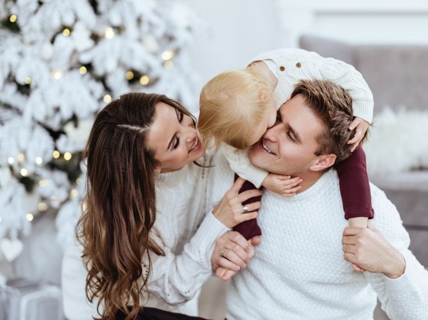 Family posing in front of a Christmas tree with snow-covered branches.