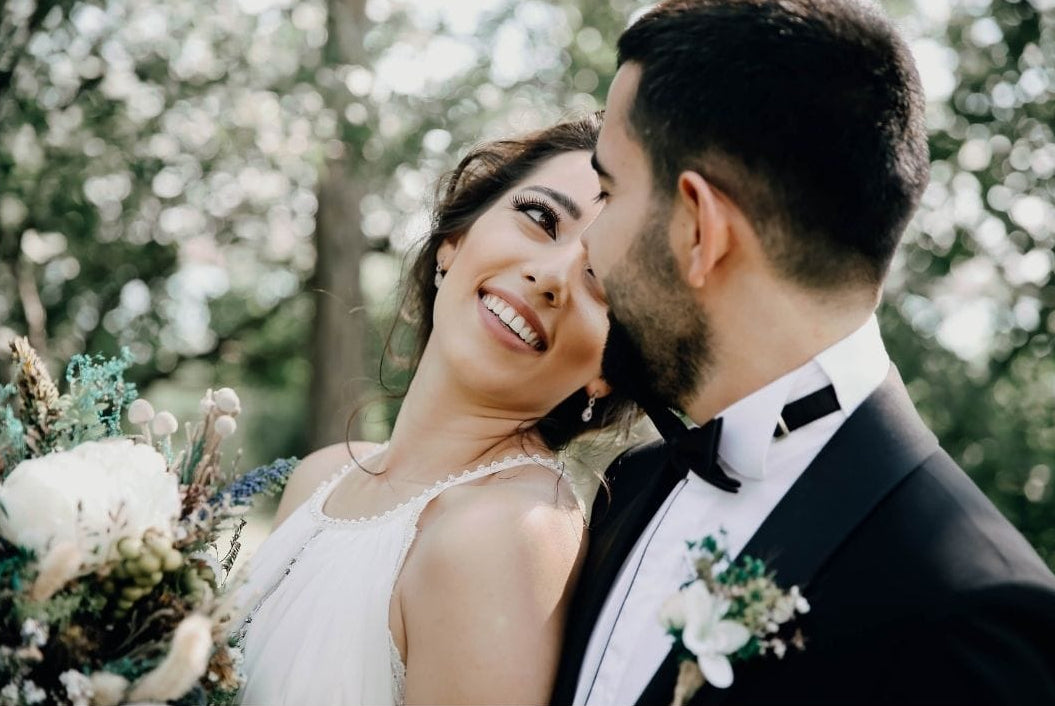 Couple in wedding attire embracing outdoors with a blurred background