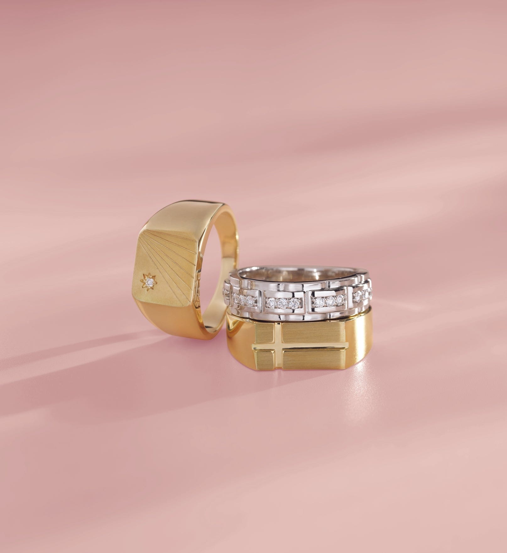 3 mens wedding bands on a pink surface