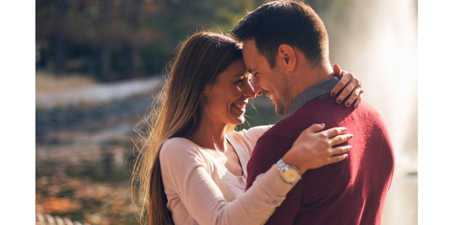 Couple embracing outdoors with a blurred natural background