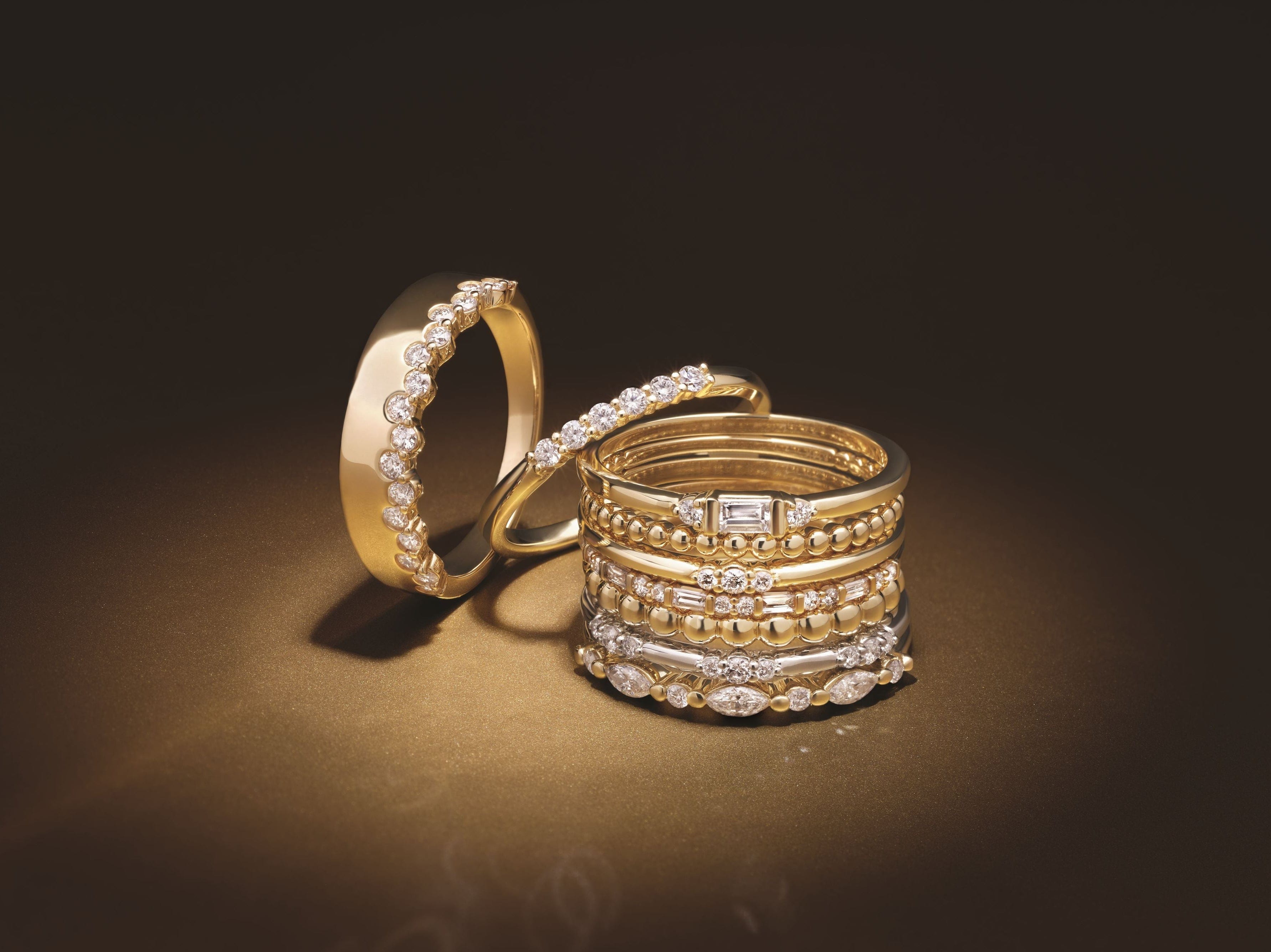 Gold fashion rings with diamond accents on a dark background