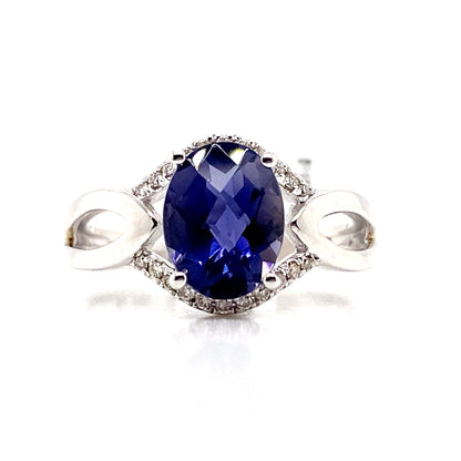 A 14K white gold ring showcasing a 1.85 ct oval Iolite center stone with natural diamond accents totaling 0.132 tw, offering unique elegance.