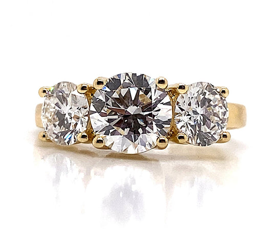 14K Yellow Gold Ring with a captivating three-stone design, featuring lab-grown diamonds totaling 3 carats, elegantly capturing and reflecting light on a white surface.