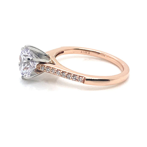 The 14K Rose Gold Ring with a White Gold Head showcases a dazzling 6.5 mm round brilliant cubic zirconia center stone, complemented by natural round brilliant accent diamonds totaling .20 carats in a stunning pave setting along the band.